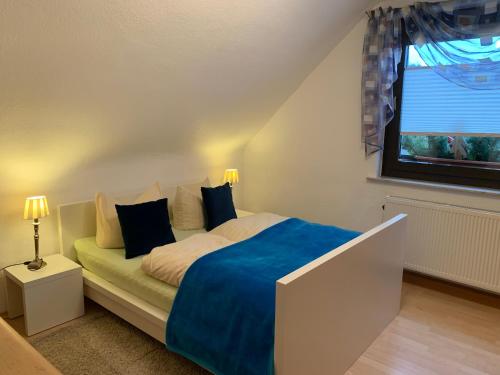 Schlafzimmer mit einem Bett mit blauer Bettwäsche und einem Fenster in der Unterkunft Ferienhaus zur Waldauer Höhe mit 3 SZ, 120qm & 40qm Balkon in Schleusingen