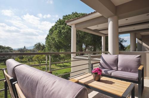 a porch with a couch and a table with flowers at La Palma Apartments - 2km from Zakynthos Town, by ZanteWize in Zakynthos Town