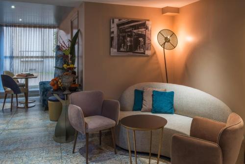 a living room with a couch and a table and chairs at Hôtel Mercure Paris Suresnes Longchamp in Suresnes