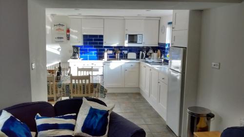 a living room with a couch and a kitchen at Penzer Cottage in Mousehole