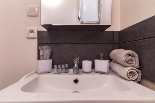 a white sink in a bathroom with a mirror and towels at Cosy'Appart - COEUR DE SEINE in Rouen