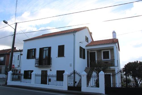 Ein weißes Haus mit einem schwarzen Zaun auf einer Straße in der Unterkunft Marquinhas House - A Queijeira in Oliveira do Hospital