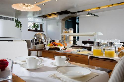 een keuken met een tafel met borden en glazen sinaasappelsap bij Hotel Palazzo Giovanelli e Gran Canal in Venetië
