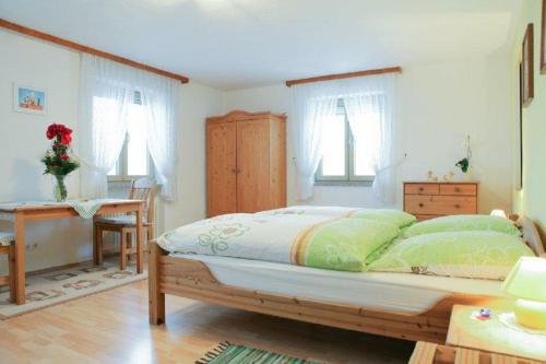 a bedroom with a bed and a desk and windows at Der Bauernhof Beim Bergler in Neureichenau