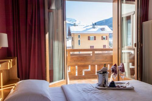 a bedroom with a bed and a large window at Hotel Santanton in Bormio