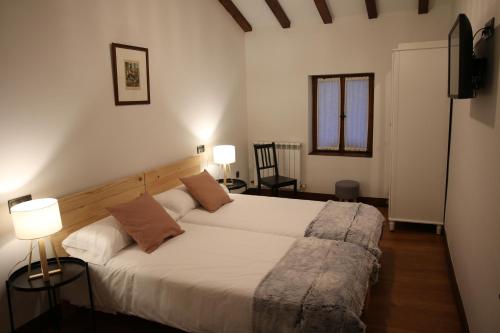 a bedroom with a bed with two lamps and two chairs at Casa Rural Iruso in Leitza