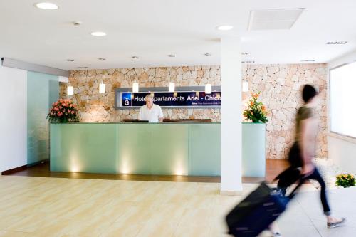 a person walking past a counter in an airport with luggage at Gavimar Ariel Chico Hotel and Apartments in Cala d´Or