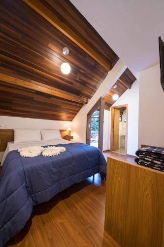 a bedroom with a blue bed with a wooden ceiling at Vila Dom Bosco in Campos do Jordão
