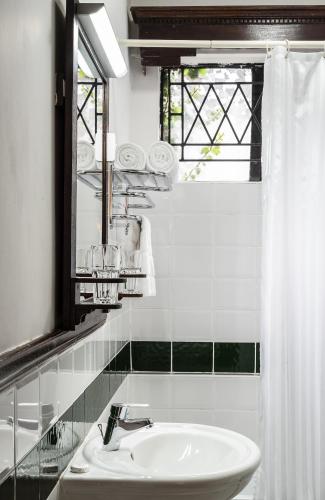 a white bathroom with a sink and a mirror at The Grand Gables in Nairobi