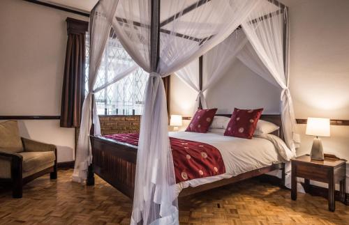 1 dormitorio con cama con dosel y ventana en The Grand Gables, en Nairobi