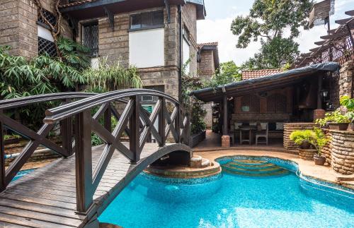 a wooden bridge over a swimming pool with a house at The Grand Gables in Nairobi