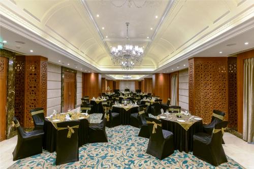a banquet hall with tables and chairs and a chandelier at Lemon Tree Premier “The Atrium” Ahmedabad in Ahmedabad
