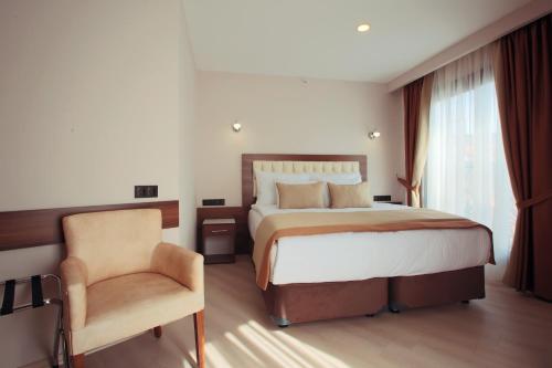a bedroom with a large bed and a chair at Hotel Paris Prestige in Izmir