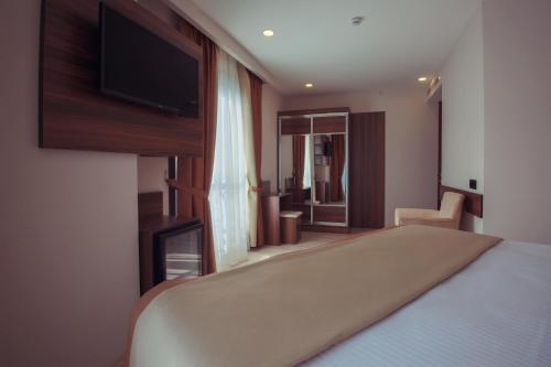 a bedroom with a bed and a flat screen tv at Hotel Paris Prestige in Izmir