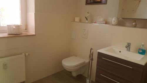 a white bathroom with a toilet and a sink at Fewo Am Marktplatz I in Eisenhüttenstadt