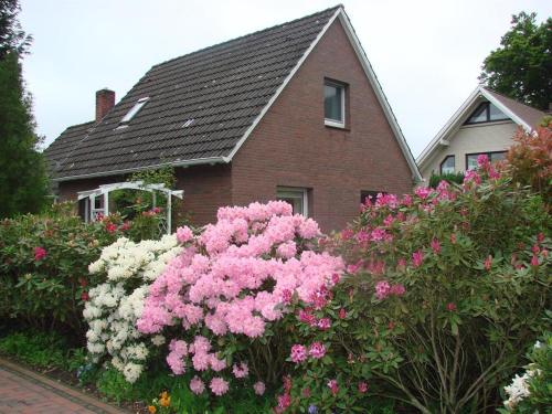 ein Haus mit rosa und weißen Blumen davor in der Unterkunft Ferienhaus "Antje" in Bad Zwischenahn