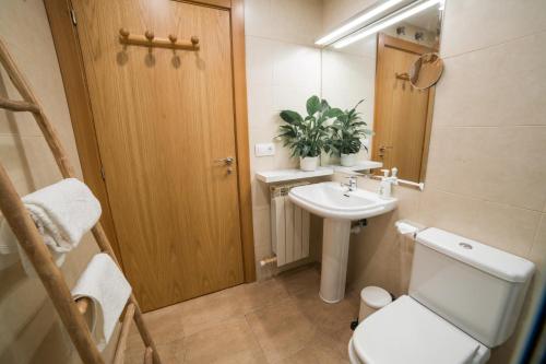 een badkamer met een toilet, een wastafel en een spiegel bij Apartamento Ático Bardenas in Arguedas