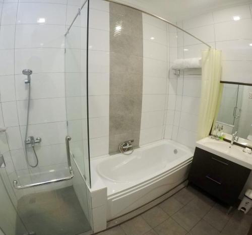 a bathroom with a shower and a tub and a sink at Astana Az-Zahrah in Bahau