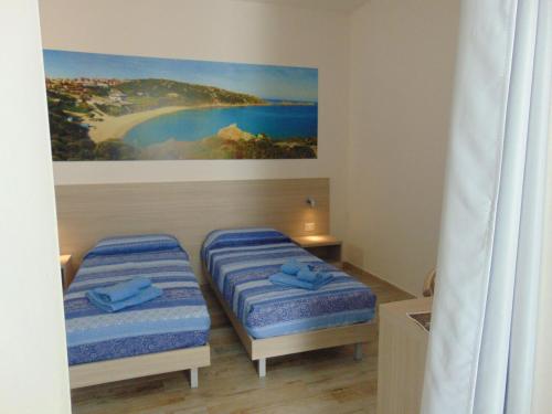a bedroom with two beds and a painting on the wall at Mio & Tuyo in Santa Teresa Gallura