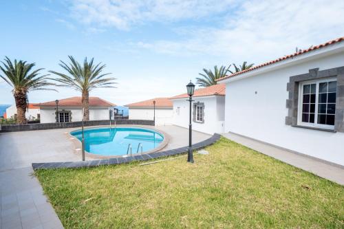 a villa with a swimming pool and palm trees at Bungalows Los Roques de Salmor in Las Puntas