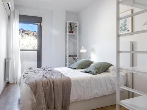 a white bedroom with a bed and a ladder at Apartamento Ático Bardenas in Arguedas