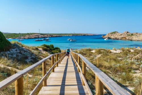a person walking down a wooden boardwalk over a beach at Sol Parc Hotel & Apartments in Son Parc