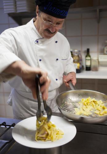 a chef in a kitchen preparing food on a plate at Hotel Tirol- Natural Idyll in Montesover