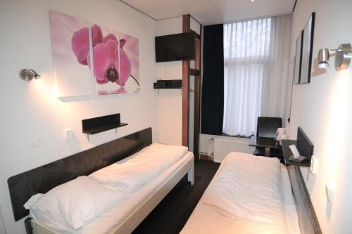a room with two beds and a window at Hotel Bienvenue in Rotterdam