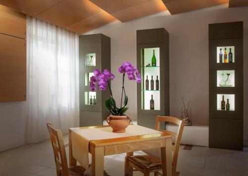 サンタンドレーアにあるBoutique Hotel Ilioのダイニングルーム(テーブル、紫の花の花瓶付)