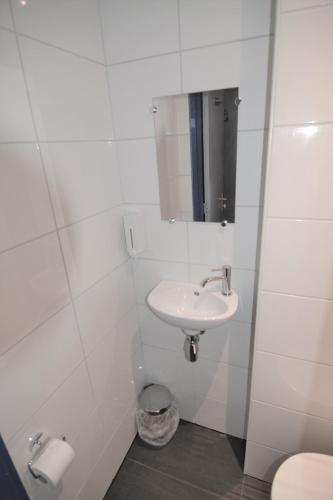 a white bathroom with a sink and a mirror at Hotel Bienvenue in Rotterdam