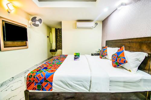 a bedroom with a large white bed with colorful pillows at FabHotel Prince Park - Nr Sajra Fort in Vellore