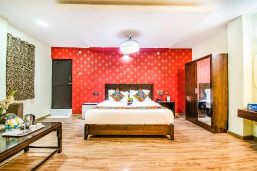 a bedroom with a bed and a red wall at FabHotel Prince Park Vellore in Vellore