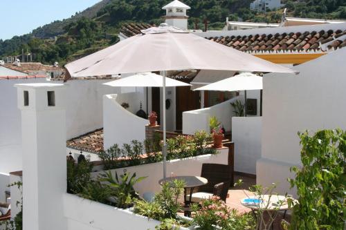 a white house with a patio with an umbrella at Boutique Hotel La Posada del Angel Ojén in Ojén