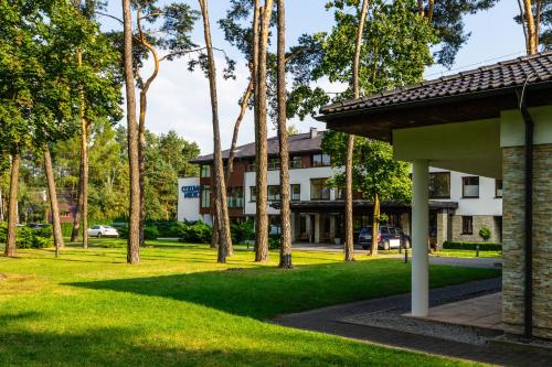 a building with palm trees in front of a yard at Columna Medica in Łask