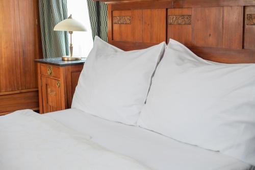 a bed with white pillows and a wooden headboard at Hotel At the Green Grape in Prague