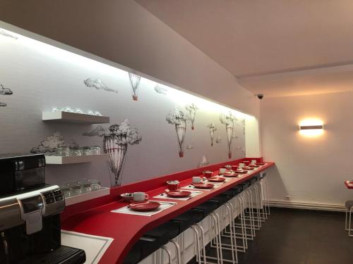 a long red table with plates and bowls on it at The Originals City, Hôtel Lecourbe, Paris Tour Eiffel (Inter-Hotel) in Paris