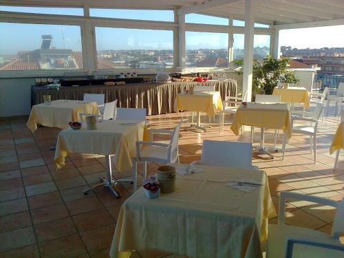 a restaurant with white tables and white chairs at Hotel L'Approdo in Anzio