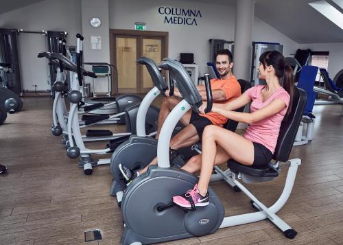 a man and woman sitting on exercise bikes in a gym at Columna Medica in Łask