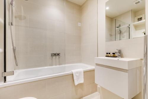 a white bathroom with a tub and a sink at Nell Gwynn Chelsea Accommodation in London