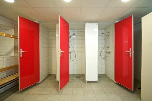 a bathroom with red doors and shower stalls at Troll Camping in Evje