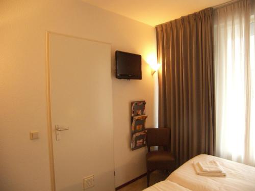 a hotel room with a bed and a television on the wall at Hotel de Markt in Valkenswaard