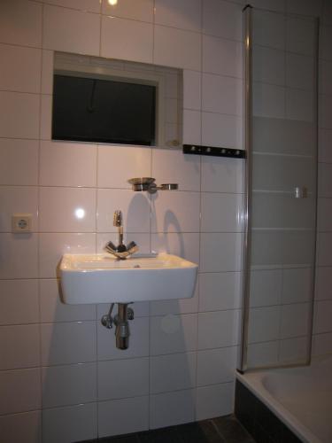 a white bathroom with a sink and a shower at Hotel de Markt in Valkenswaard