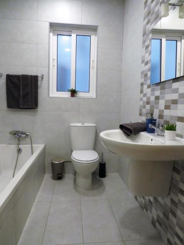 a white bathroom with a toilet and a sink at SeaLine in St. Paul's Bay