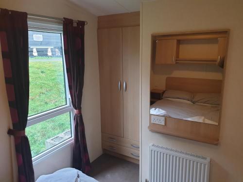 ein kleines Schlafzimmer mit einem Bett und einem Fenster in der Unterkunft Seaview caravans in Aberystwyth