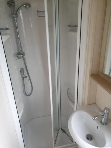 a shower with a glass door next to a sink at Seaview caravans in Aberystwyth