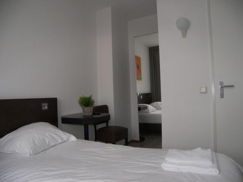 a bedroom with a bed and a table with a chair at Hotel de Markt in Valkenswaard