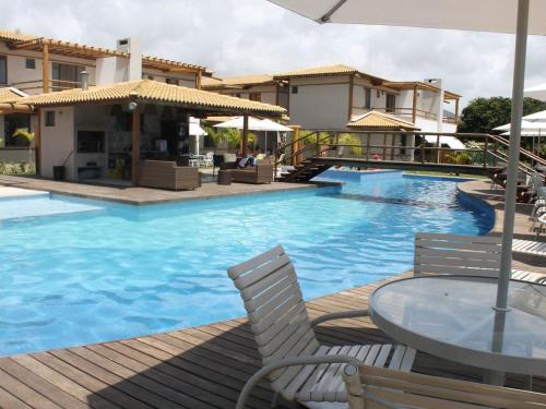 a swimming pool with a table and chairs and some buildings at Village Duplex Confortável e Acolhedor junto a Natureza - Condomínio Reserva das Ilhas in Itacimirim