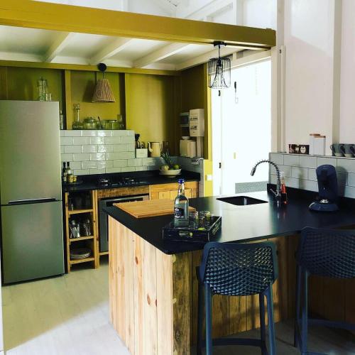 a kitchen with a refrigerator and a counter with chairs at Ti coin paradis in Anse-Bertrand