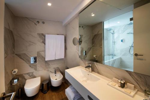 a bathroom with a sink and a toilet and a mirror at Occidental Vigo in Vigo