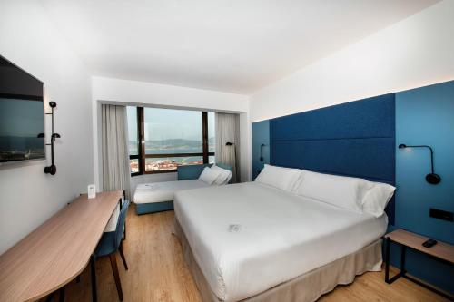 a bedroom with a large white bed and a blue wall at Occidental Vigo in Vigo